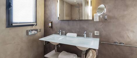 A modern bathroom with a large mirror, two sinks, and a towel rack.