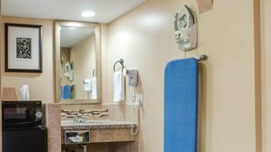 A bathroom with a sink, mirror, towel rack, and a blue towel hanging on the wall. - Sky Palm Motel (Orange)