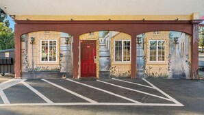 A building with a red door, three arched windows, and a yellow awning. - Sky Palm Motel (Orange)