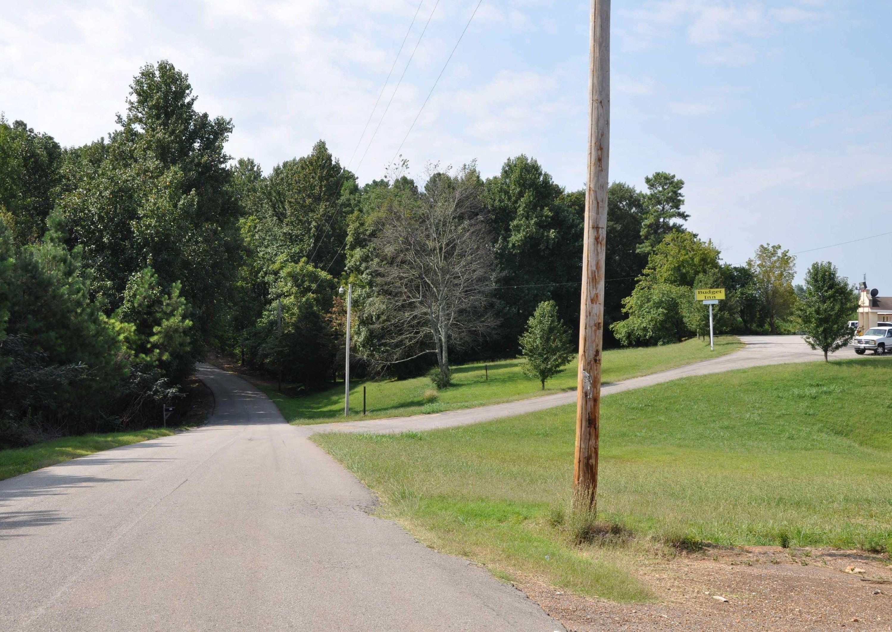 A rural road with a sign for Budget Inn.