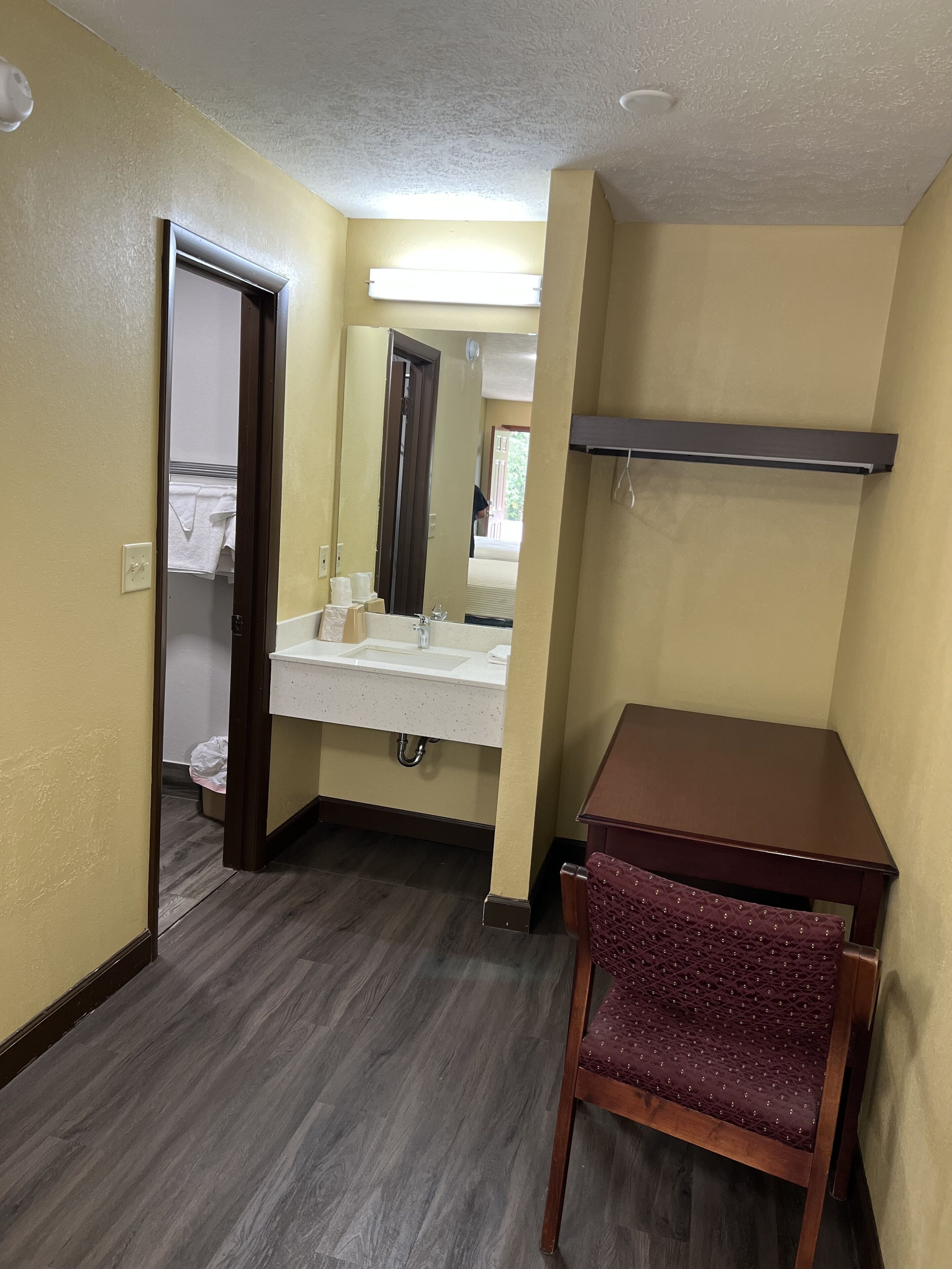 Une salle de bain avec une chaise en bois, un lavabo et un miroir.
