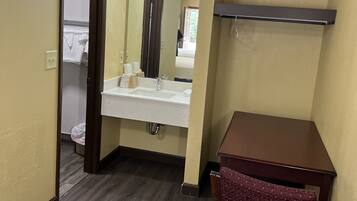 Une salle de bain avec une chaise en bois, un lavabo et un miroir.