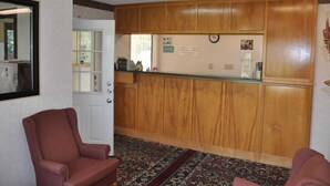 Un espace d’accueil avec un lambris en bois, un comptoir d’accueil, une horloge et un panneau indiquant les règles concernant les animaux de compagnie.
