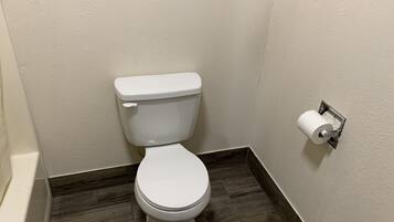 A white toilet with a paper towel holder on the wall.