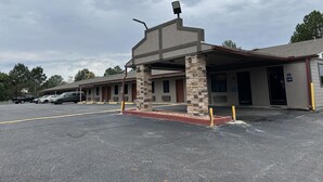 Un motel avec une façade en pierre, de nombreuses chambres et un parking.