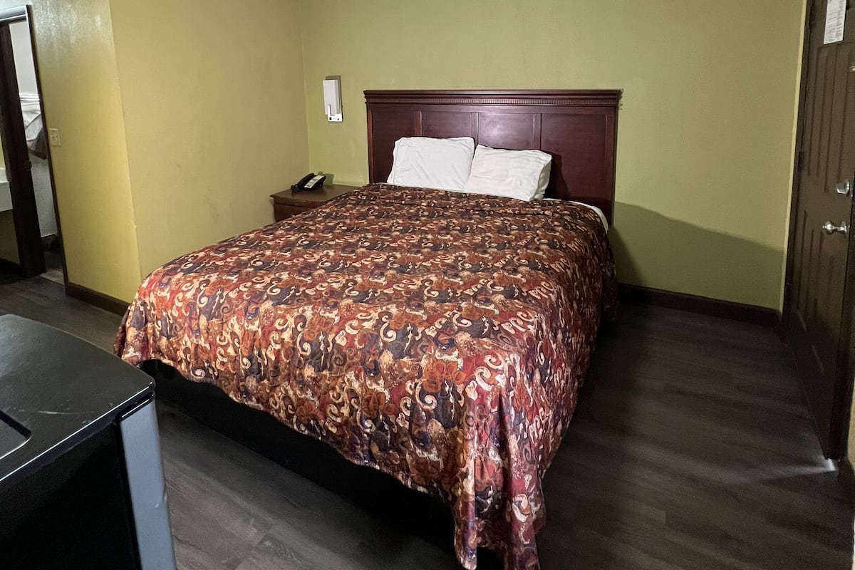 Ein Hotelzimmer mit Bett, Schreibtisch und Tür.