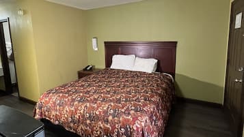 Hotellihuone, jossa on sänky, työpöytä ja ovi.