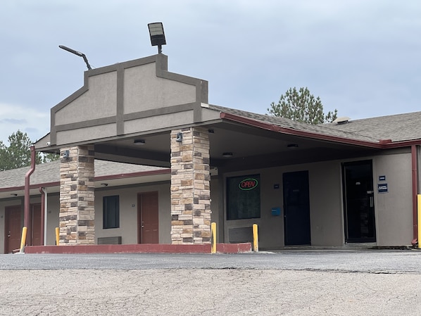 A motel with a simple facade, a covered entrance, and a visible 'OPEN' sign.