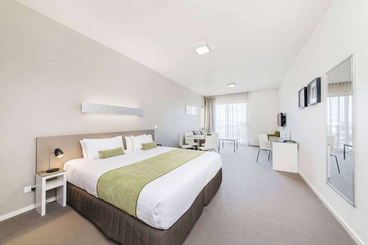 Una habitación de hotel moderna con una cama grande, mesitas de noche, un escritorio y una silla.