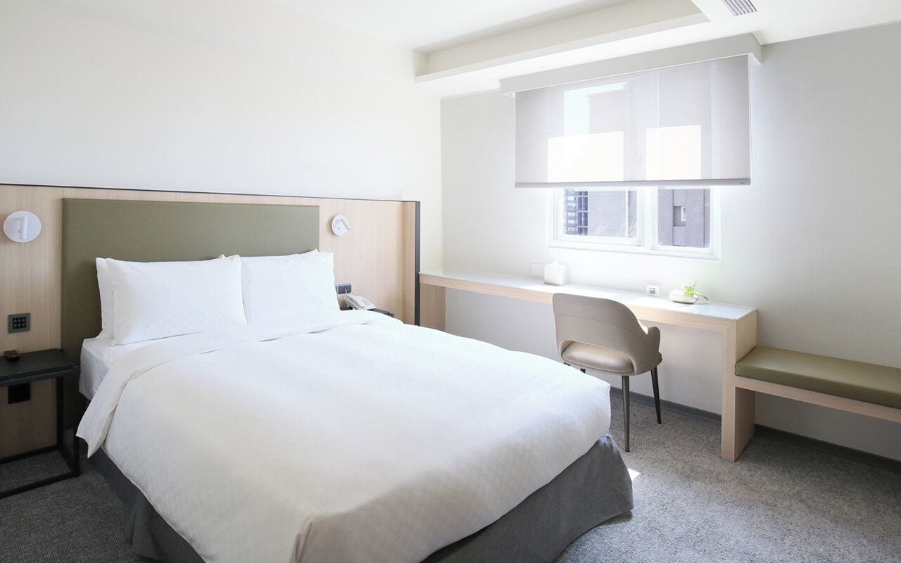 Una habitación de hotel con cama, escritorio y silla.