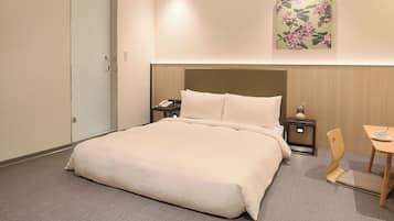 A hotel room with a large bed, bedside tables, a chair, and a small table.