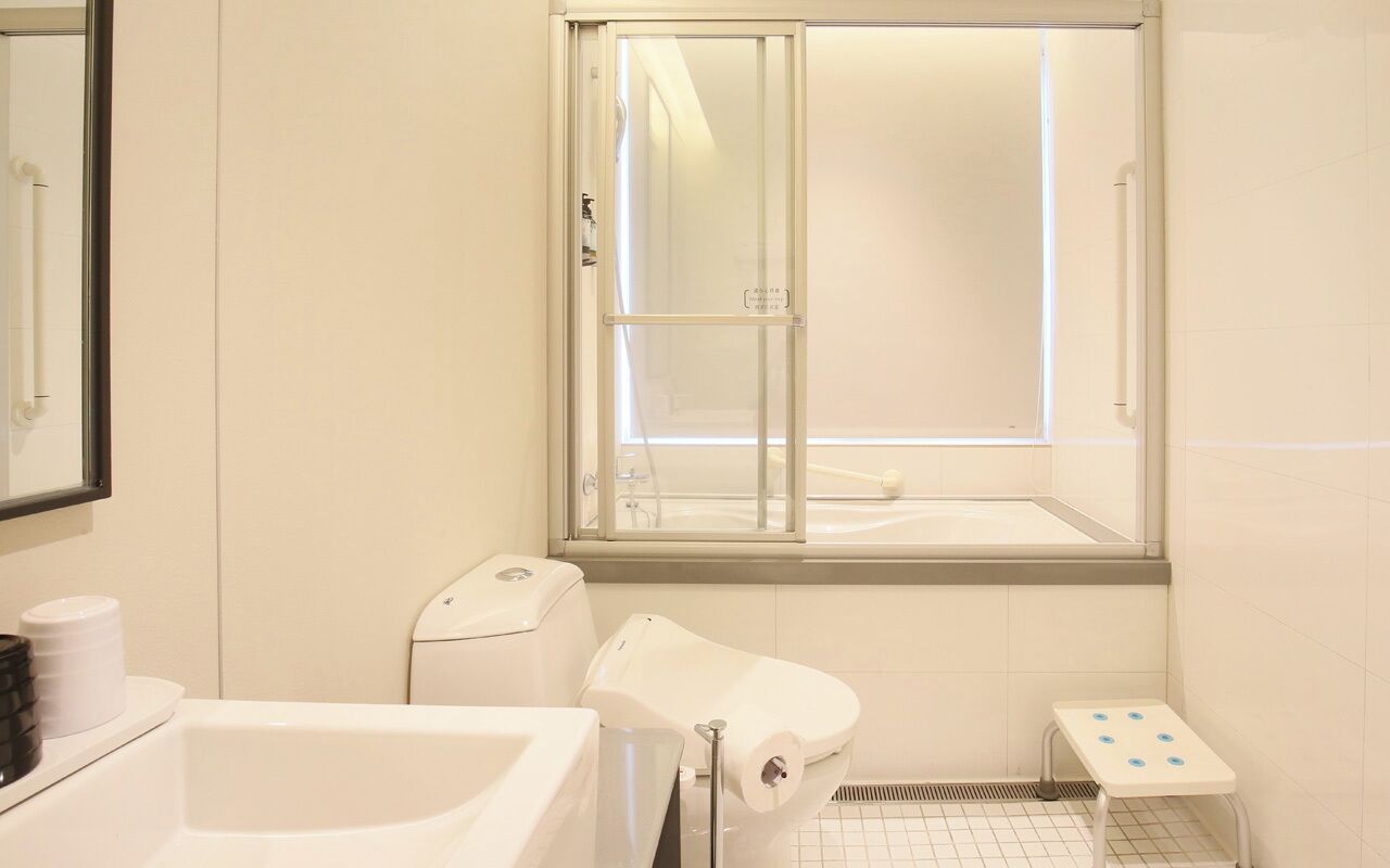 A bathroom with a bathtub, toilet, and a window with a view.