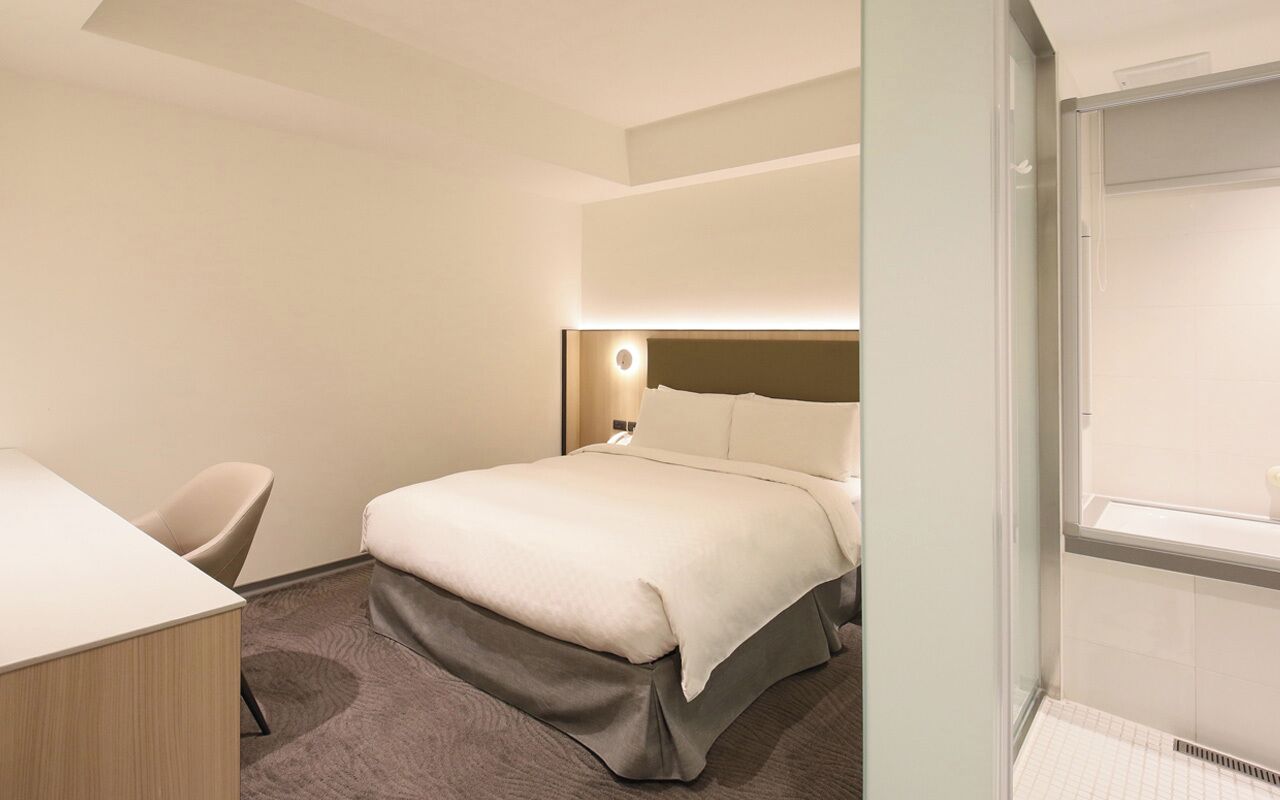 Una camera d'albergo con un letto, una scrivania e una sedia.