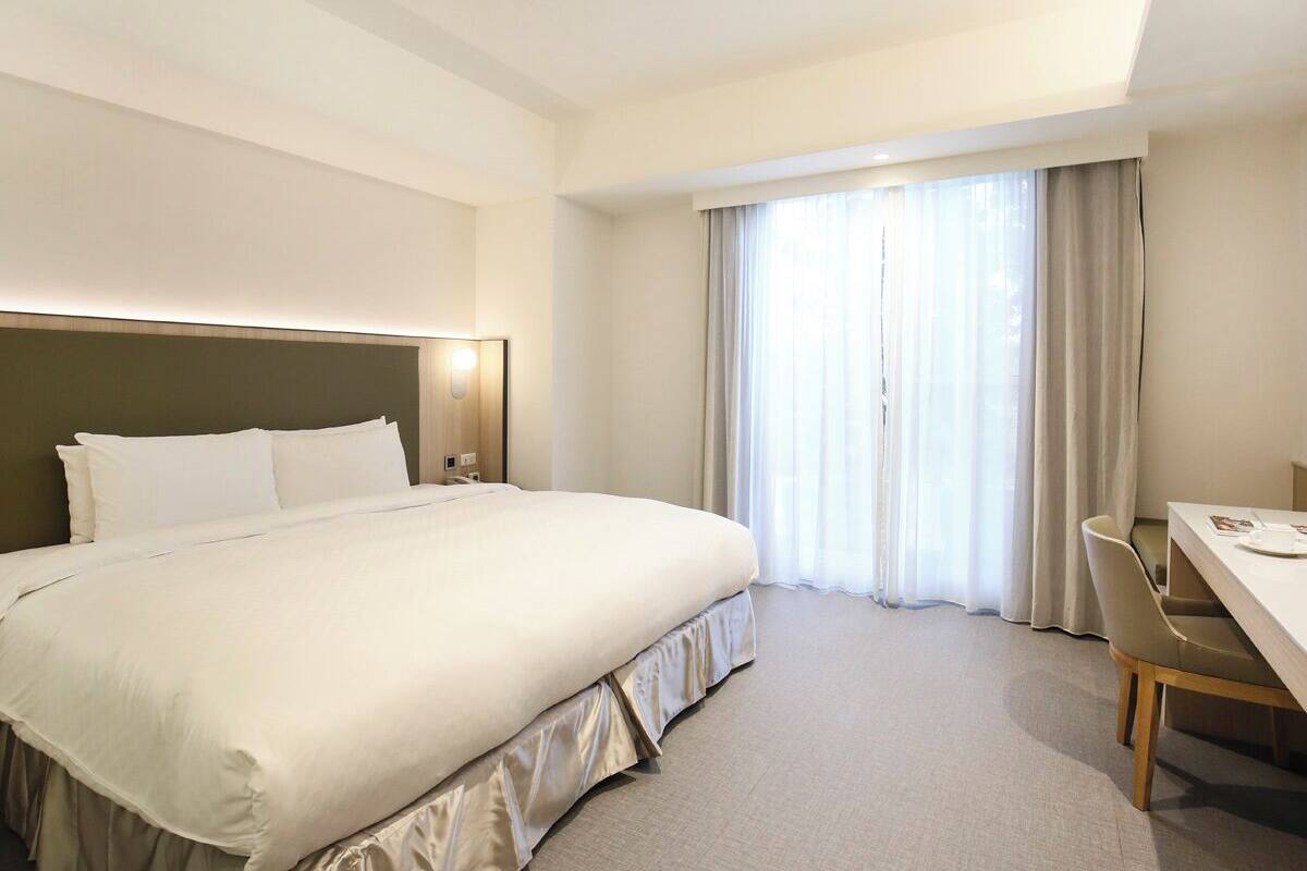 Quarto de hotel com uma cama grande, uma mesa e uma cadeira.