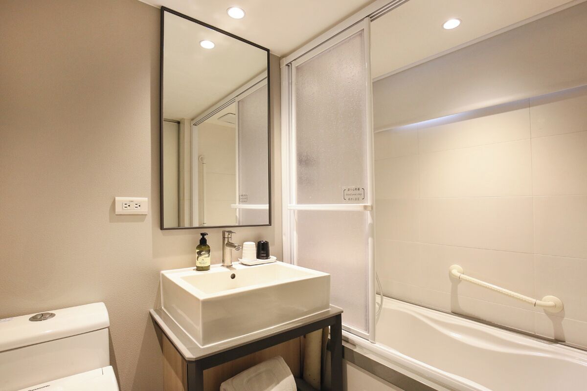 A bathroom with a white sink, mirror, and bathtub.