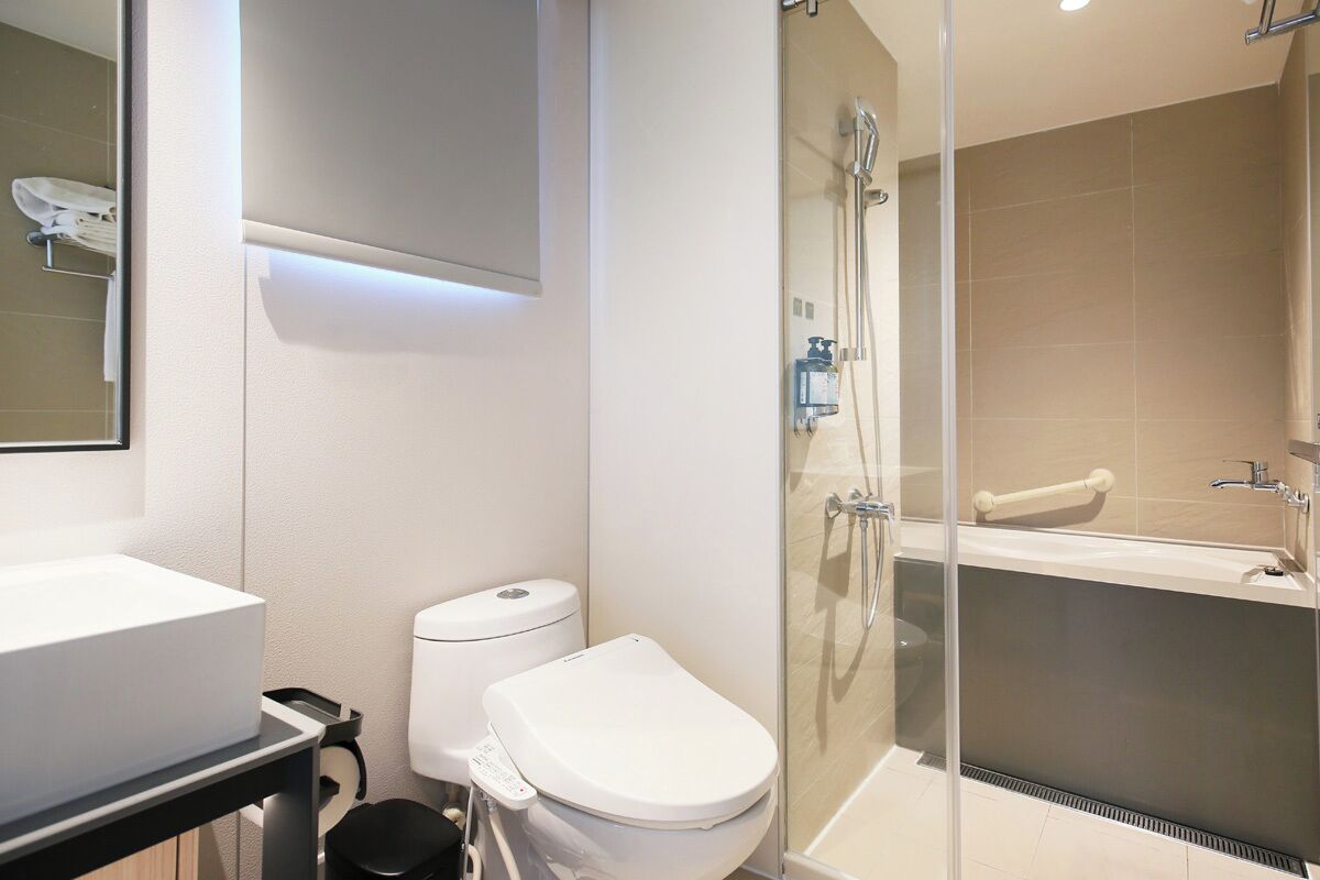 A modern bathroom with a glass-enclosed shower, a white toilet, and a large sink.