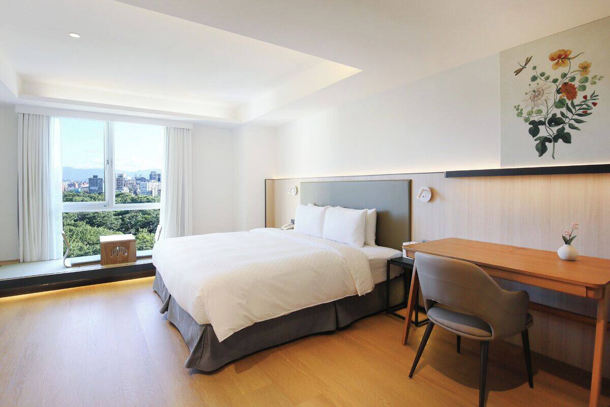 Quarto de hotel moderno com uma cama grande, uma escrivaninha e uma cadeira.