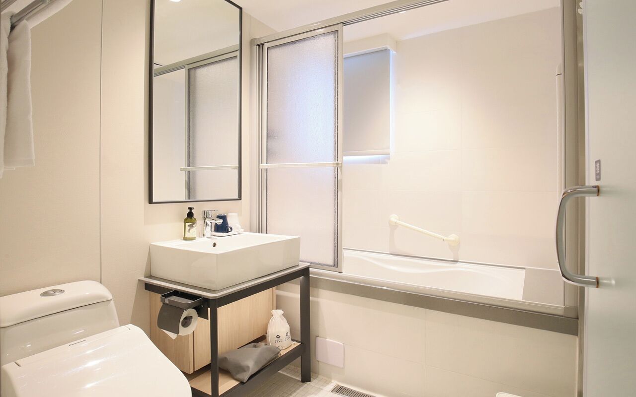 Un baño moderno con inodoro, lavamanos y espejo.