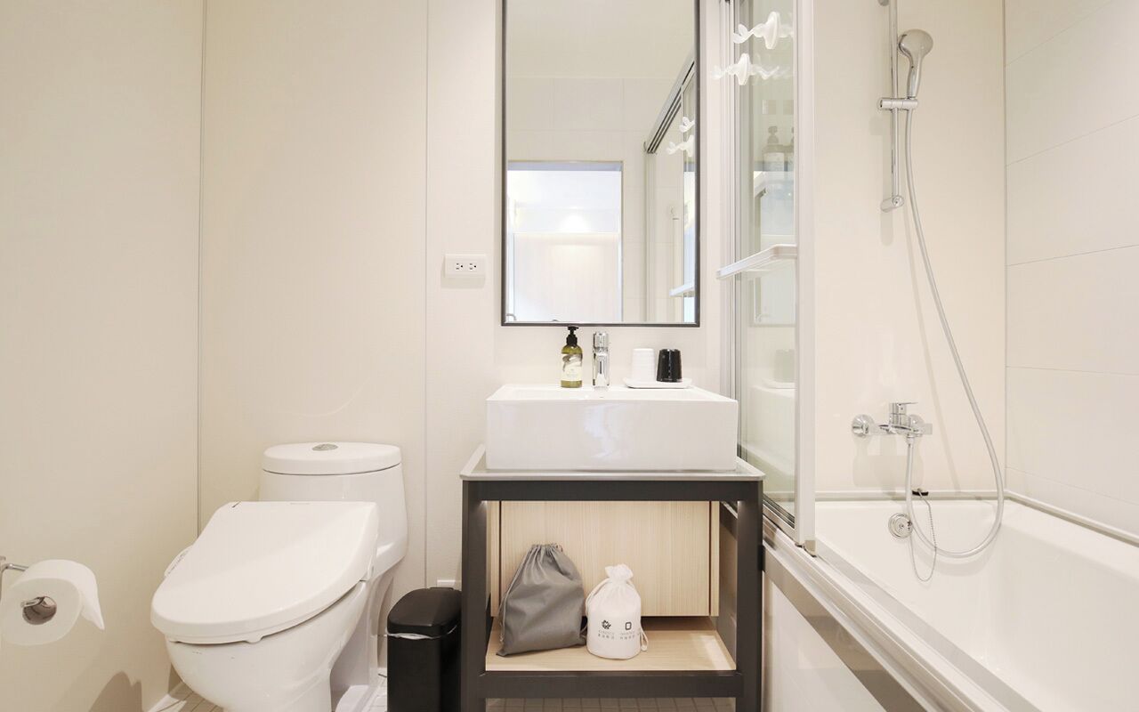 A modern bathroom with a toilet, sink, mirror, and shower.