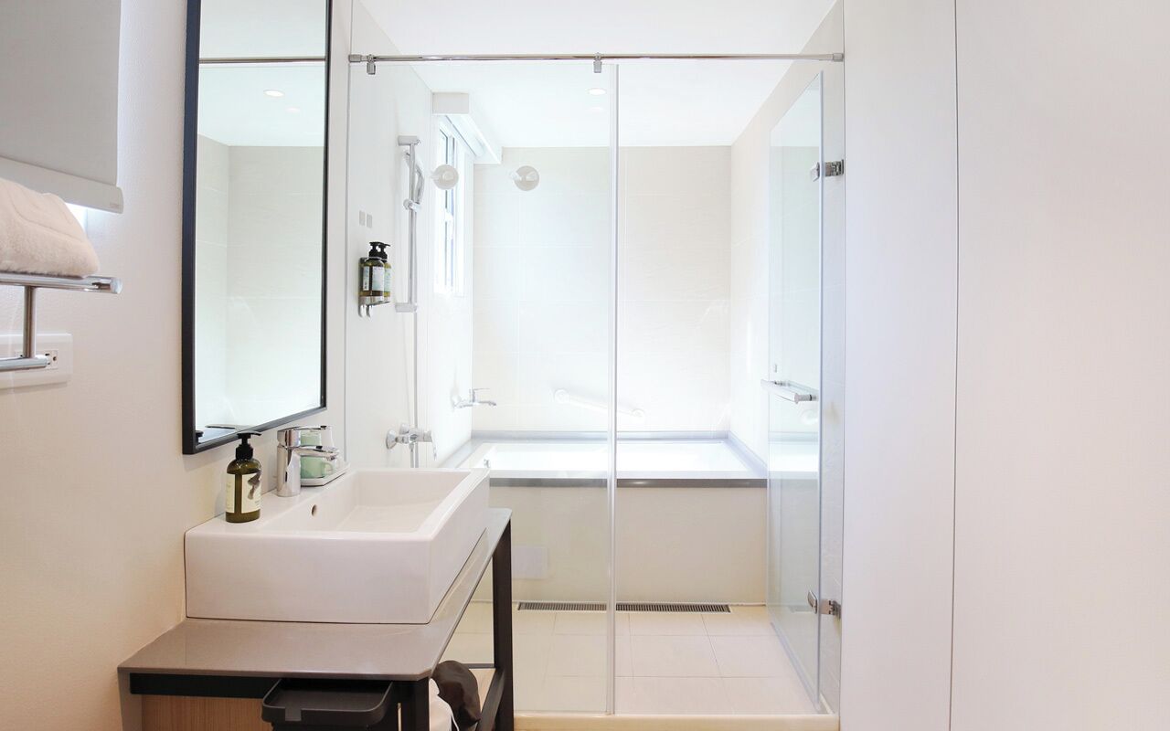 A modern bathroom with a glass shower enclosure, a white sink, and a mirror.