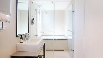 A modern bathroom with a glass shower enclosure, a white sink, and a mirror.