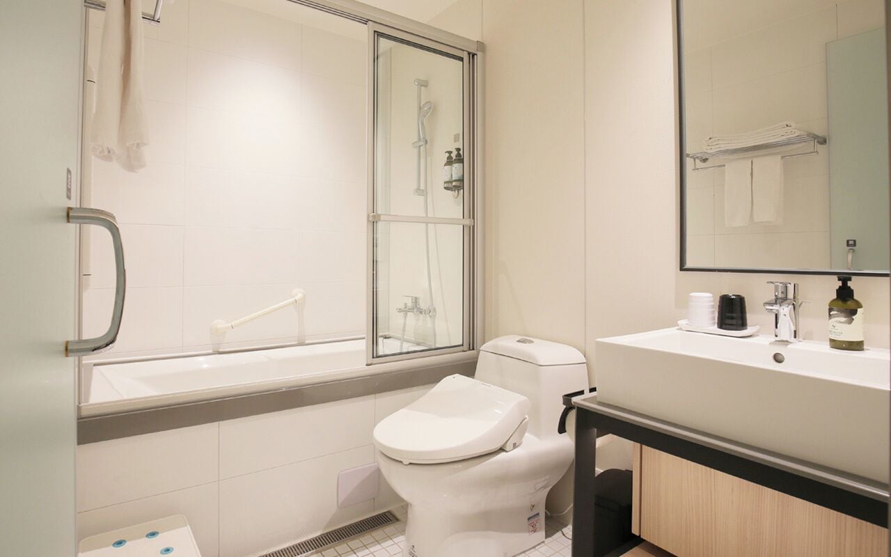 A modern bathroom with a glass-enclosed shower, a white toilet, and a sink with a mirror above it.