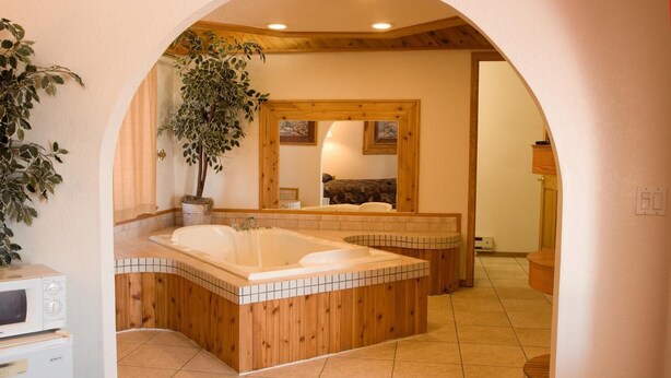 A bathroom with a wooden vanity, a large bathtub, and a mirror.