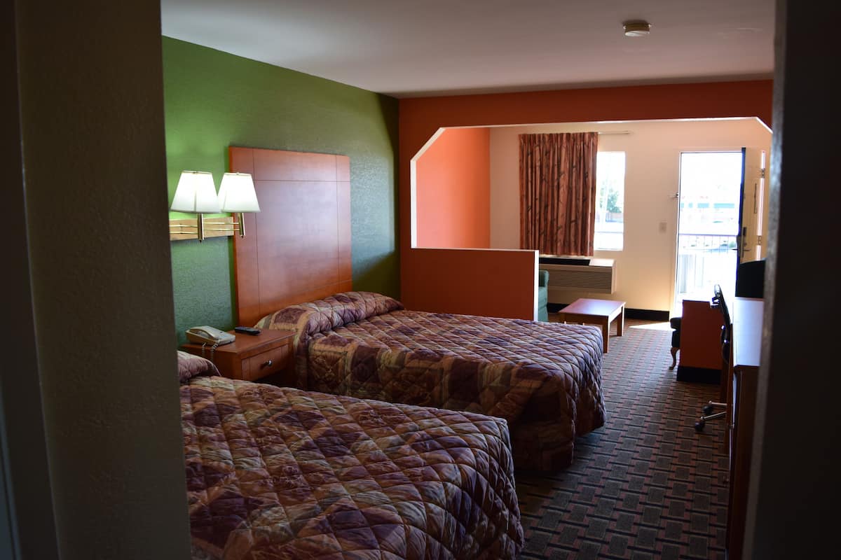 A hotel room with two beds, a desk, a chair, a telephone, and a window with curtains.