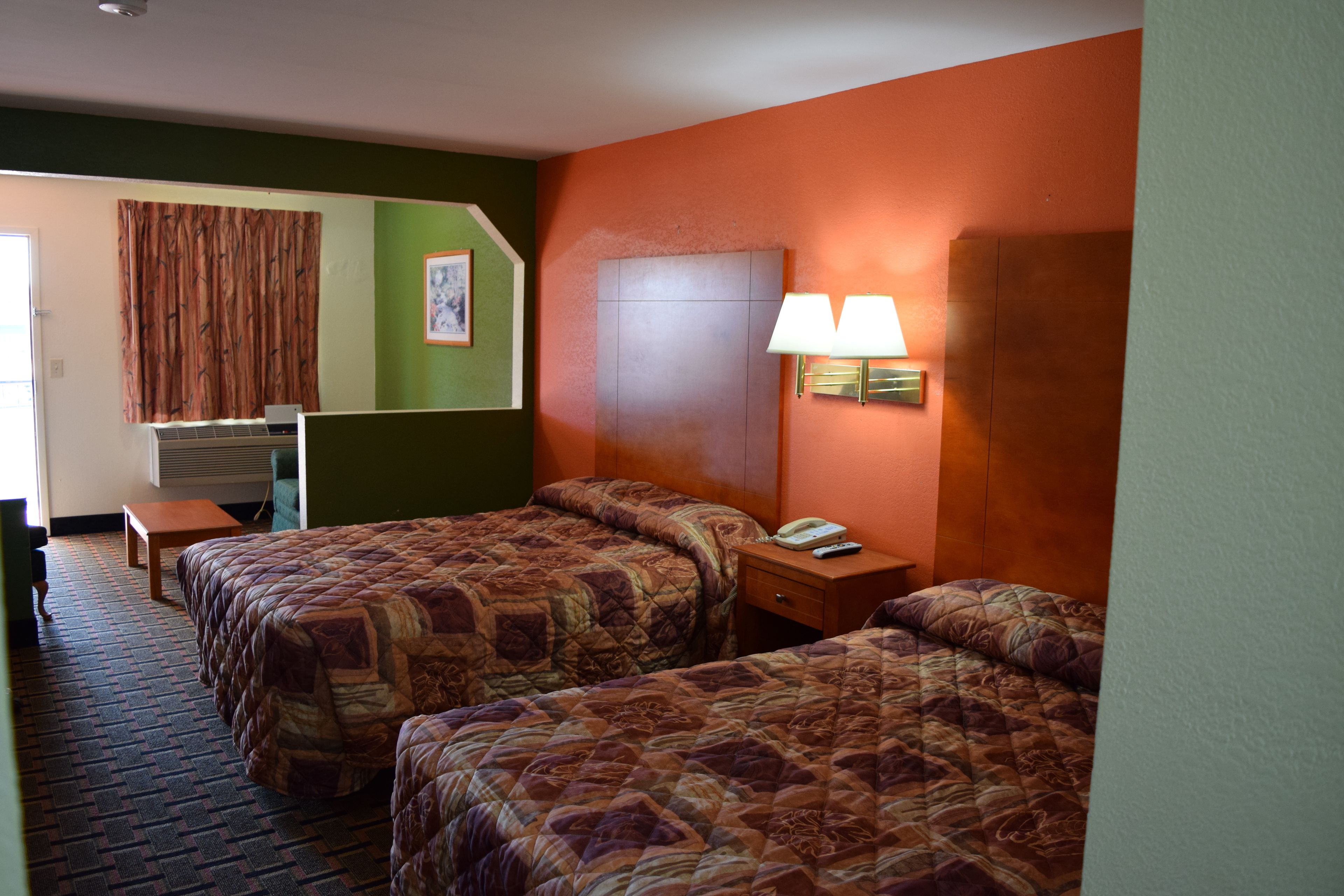 Habitación de hotel con dos camas, un escritorio, una silla y una lámpara.