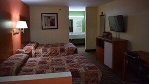 Ein Hotelzimmer mit zwei Betten, einem Schreibtisch, einem Fernseher und einem kleinen Kühlschrank.