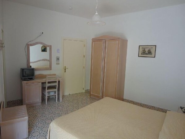 A bedroom with a bed, a wardrobe, a desk with a television, a mirror, and a door. - Hotel Candia (Casamicciola Terme)