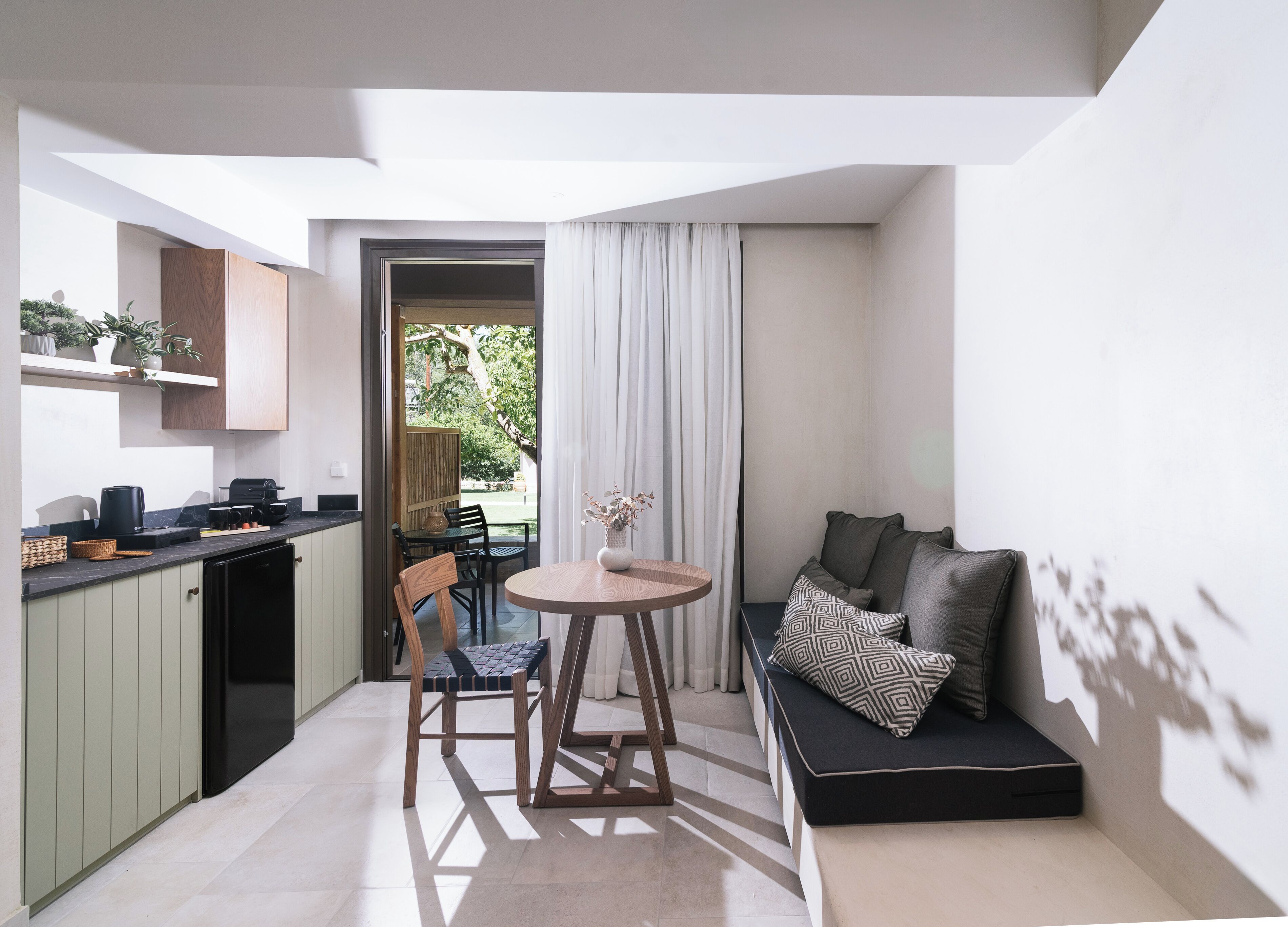 A compact living space with a kitchenette, a dining area, and a seating area with a sofa and cushions.