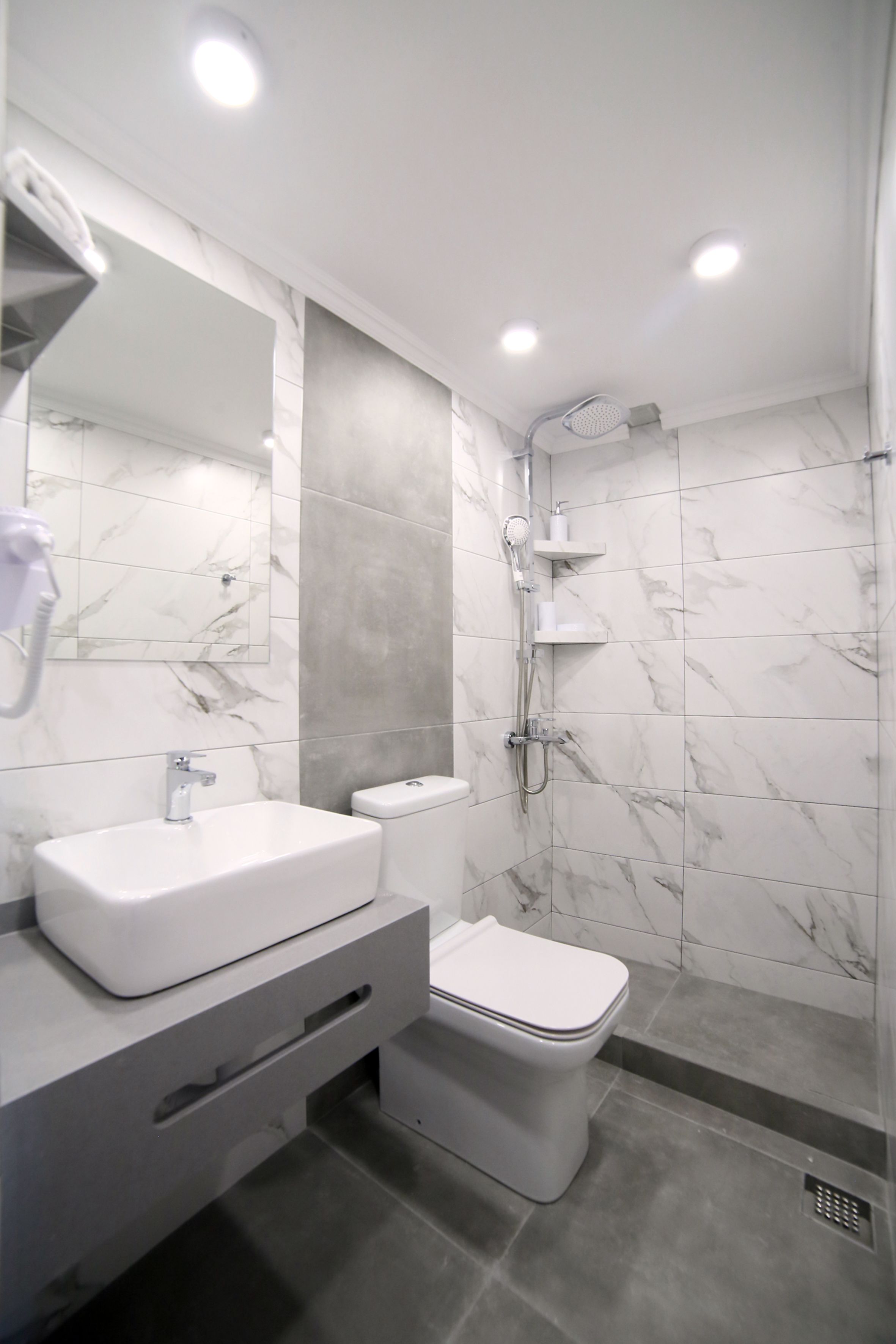 A modern bathroom with a marble sink, toilet, and shower.