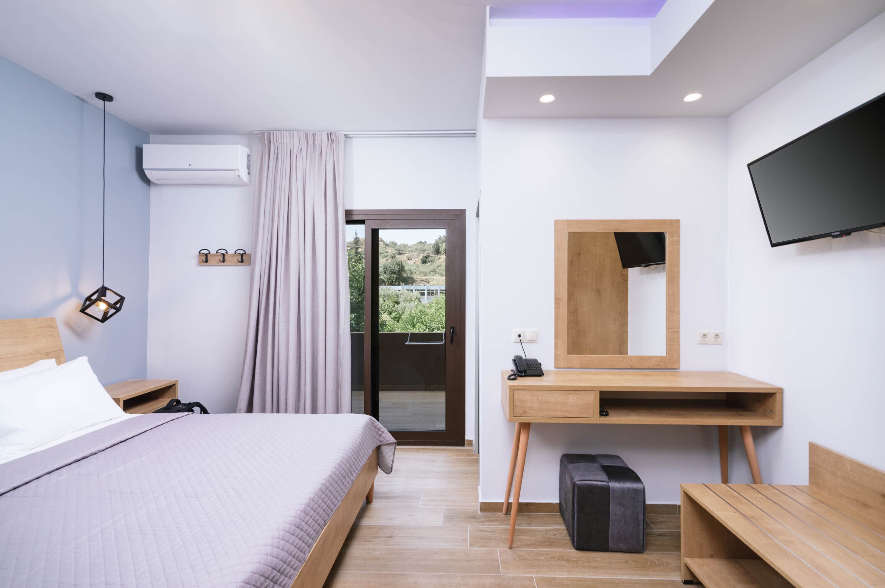 A modern hotel room with a bed, desk, and TV.