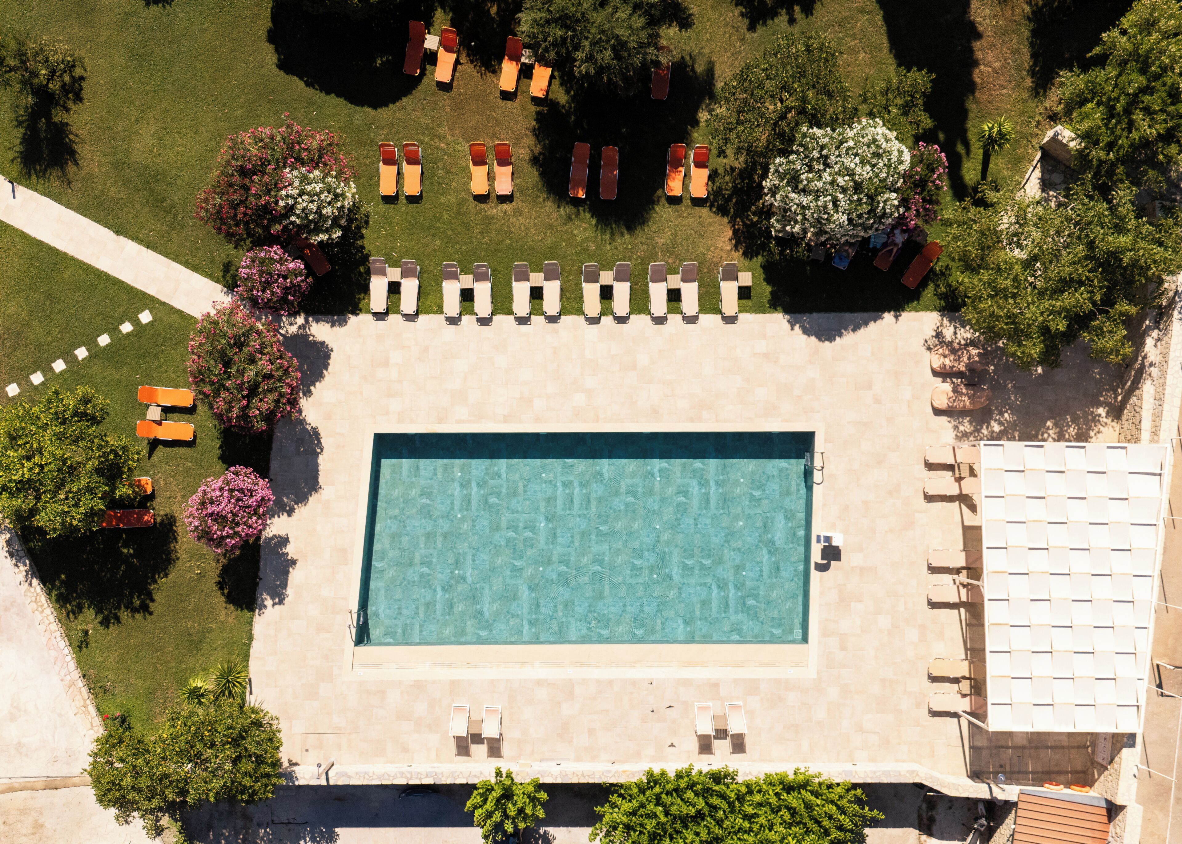 An aerial view of a swimming pool surrounded by lounge chairs and trees.