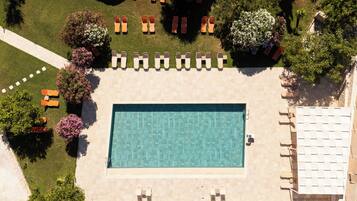 An aerial view of a swimming pool surrounded by lounge chairs and trees.