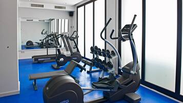 Ein Fitnessstudio mit Cardiogeräten, Gewichtsbänken und Kurzhanteln.