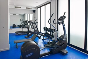 Ein Fitnessstudio mit Cardiogeräten, Gewichtsbänken und Kurzhanteln.