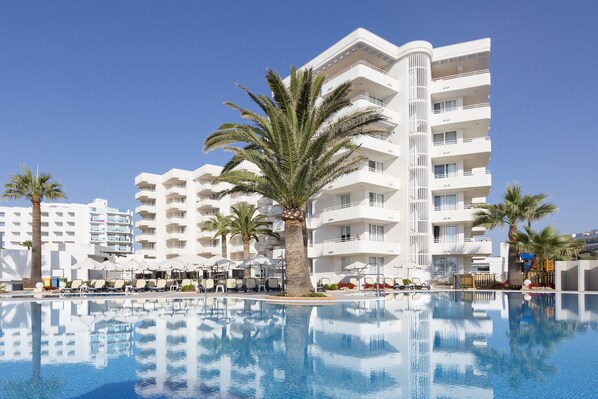 Un resort con piscina, palme e edifici a più piani colorati di bianco.