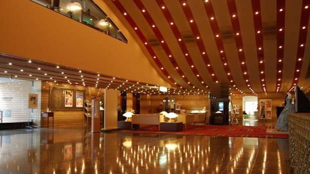 A spacious lobby with a polished floor, a reception desk, and a high ceiling with red and white stripes. - Fukuoka Garden Palace (Fukuoka)