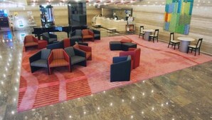 A lobby with a red carpet, multiple seating areas with chairs and sofas, a reception desk, and a large wall mural. - Fukuoka Garden Palace (Fukuoka)