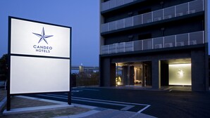 A modern hotel entrance with a prominent sign, a multi-story building, and a well-lit driveway. - Candeo Hotels Kameyama (Kameyama)