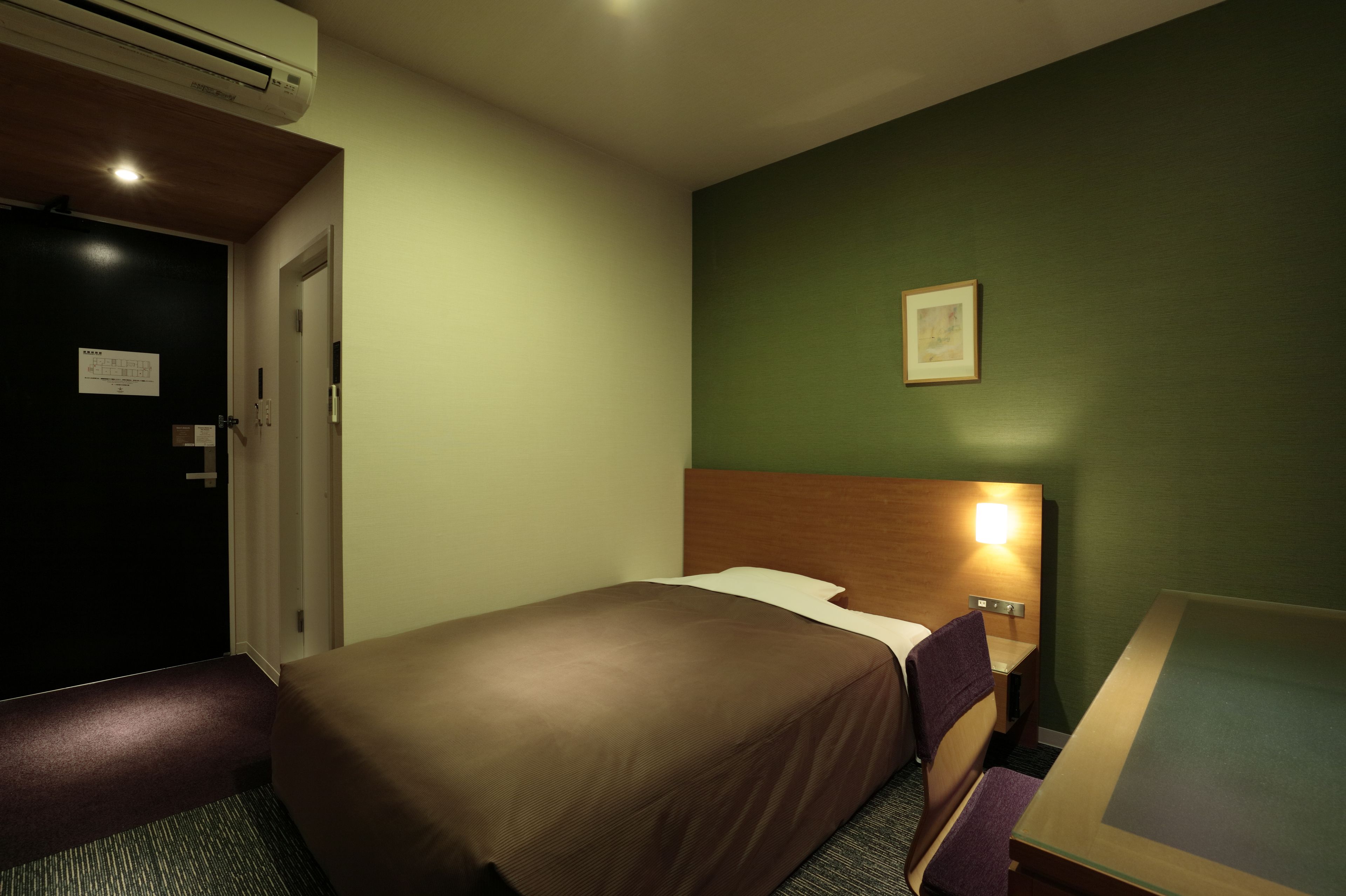 Une chambre d’hôtel avec un lit, un bureau et une chaise.