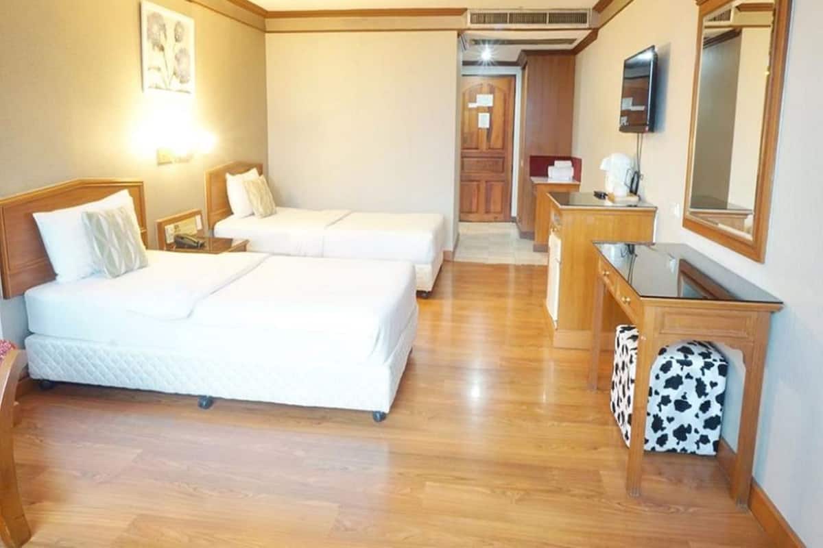 A hotel room with two beds, a desk, a mirror, and a small bathroom area.