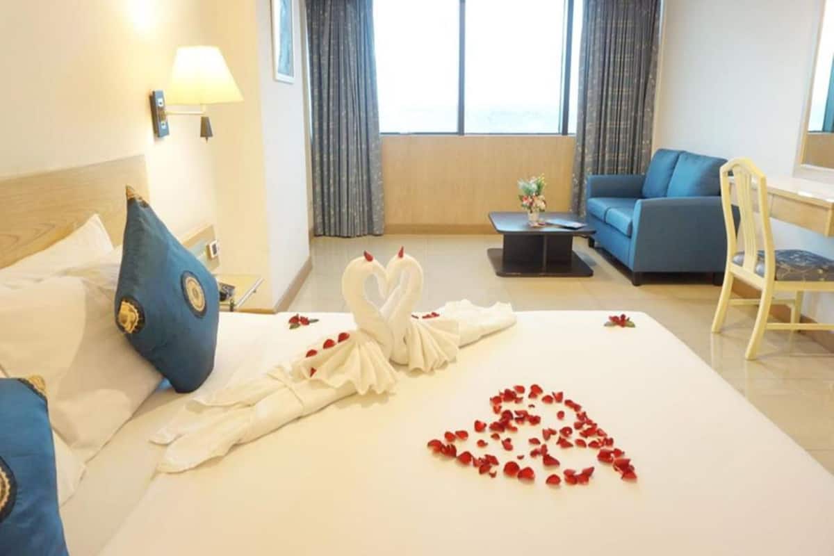 A hotel room with a bed, a sofa, a desk, and a chair.