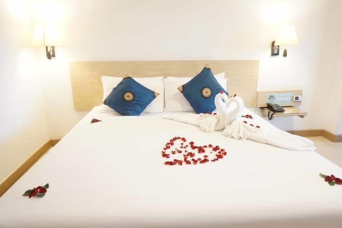 A hotel room with a neatly made bed, two pillows, a bedside table with a lamp, and a phone.