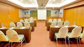 A conference room with tables, chairs, and a projector screen.