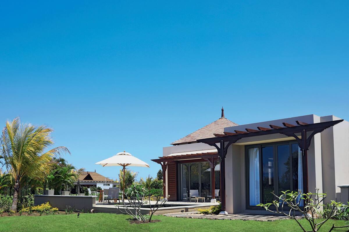Une villa moderne dotée d’un patio couvert, d’une piscine et d’un aménagement paysager luxuriant.