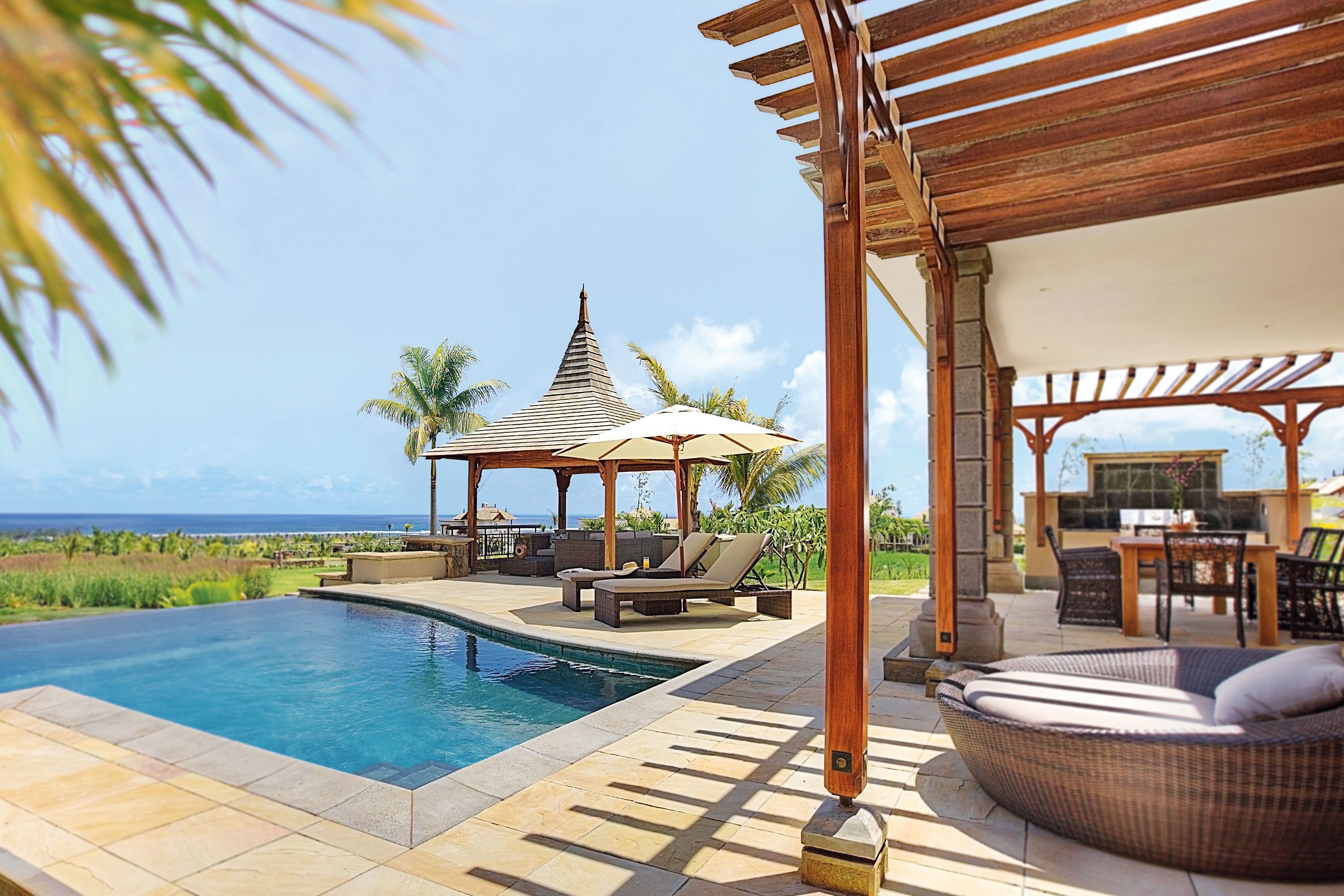 A pool area with a gazebo, lounge chairs, and a view of the ocean.