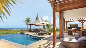 A pool area with a gazebo, lounge chairs, and a view of the ocean.